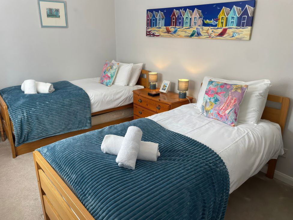 A bedroom with two single beds and a painting at Sunrise Apartment in Weymouth