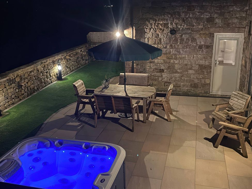 An outdoor area with a hot tub and dining table at Small Lane Cottage Blackwood Hill near Endon