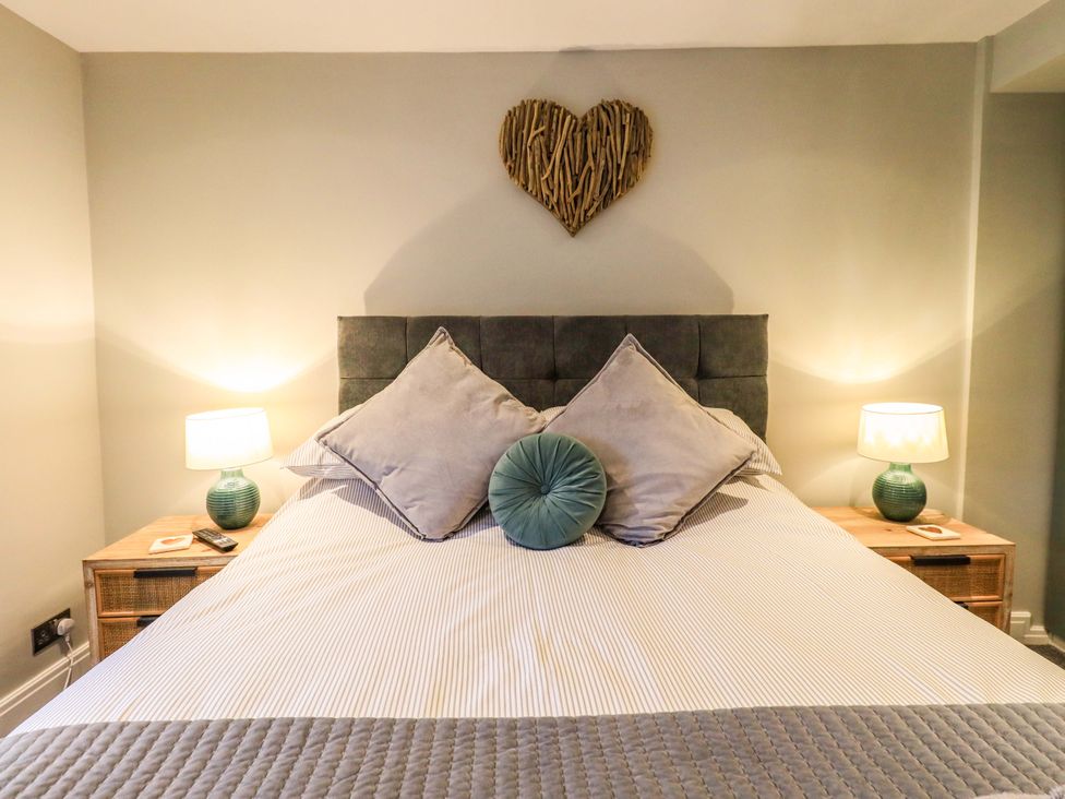 A bedroom with a bed and nightstands at West View in Leasgill near Milnthorpe