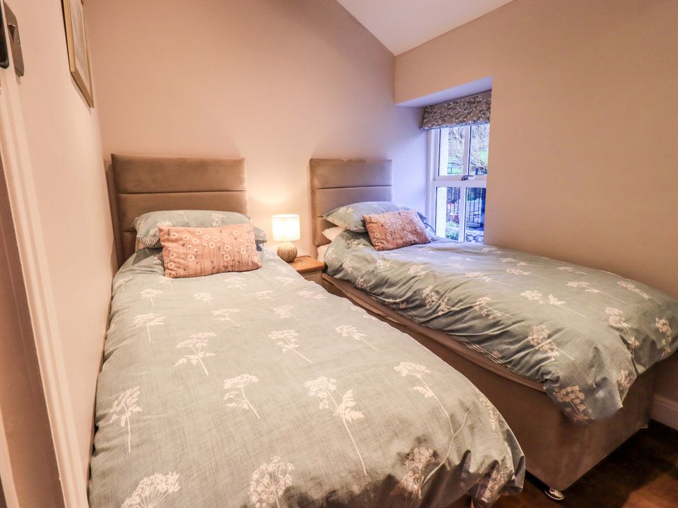 A bedroom with two single beds and a lamp at West View in Leasgill near Milnthorpe