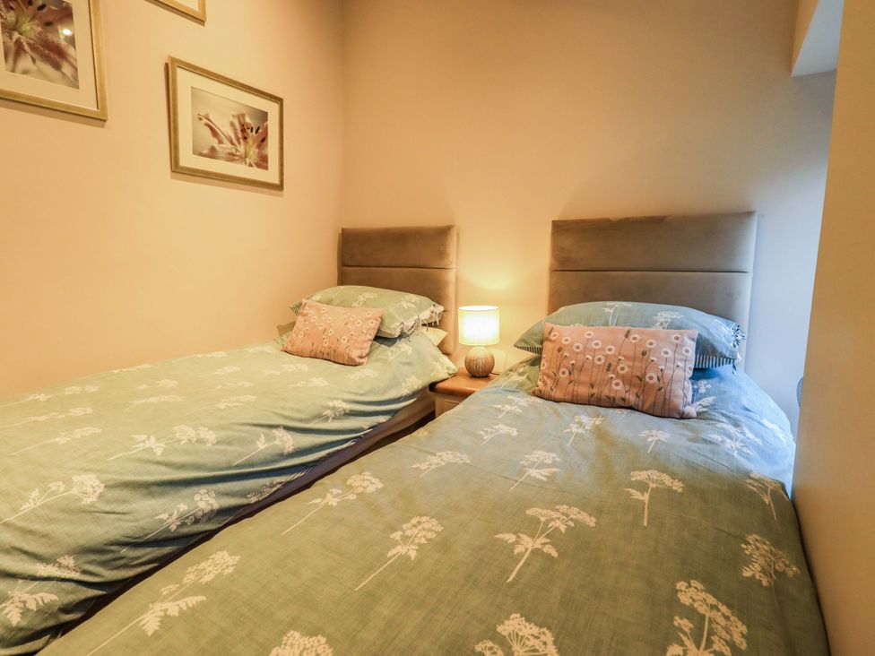 A bedroom with two single beds and a bedside lamp at West View in Leasgill near Milnthorpe