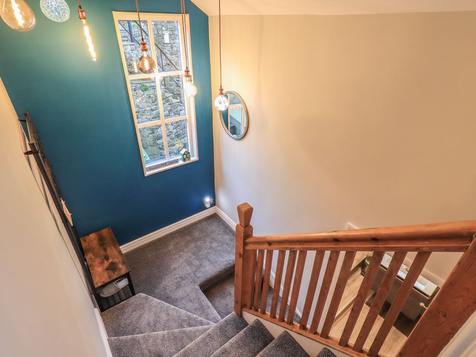 A staircase with wooden handrail and light fixtures at West View in Leasgill near Milnthorpe