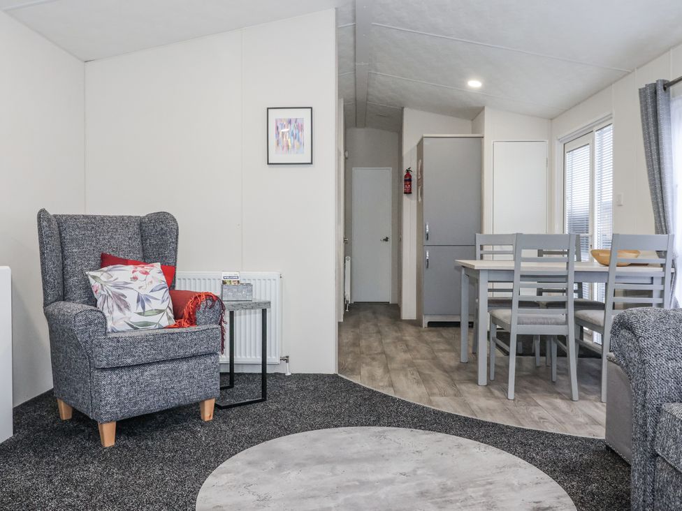 A living room with an armchair, table, and chairs at Happy Daze in Carnaby near Bridlington