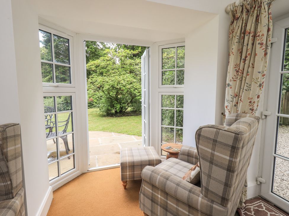 A conservatory with armchairs and garden view at The Old Post House at Low Stott Park near Newby Bridge
