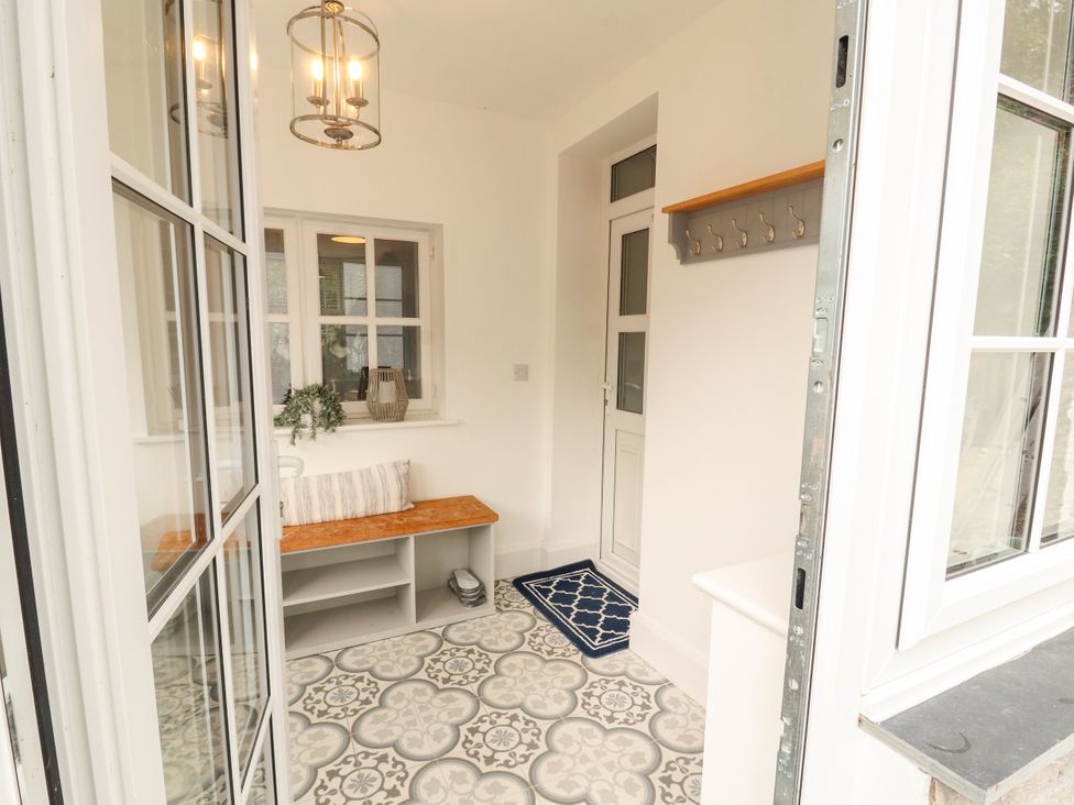 An entrance hall with a bench and coat hooks at The Old Post House at Low Stott Park