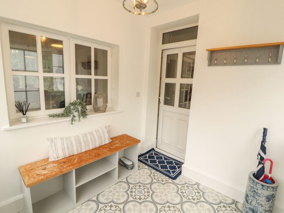A hallway with a bench and coat hooks at The Old Post House at Low Stott Park