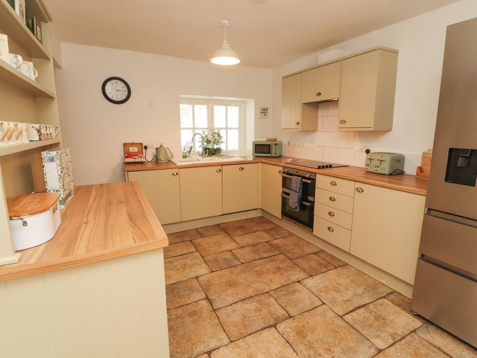 A kitchen with countertops, appliances and a clock at The Old Post House at Low Stott Park near Newby Bridge