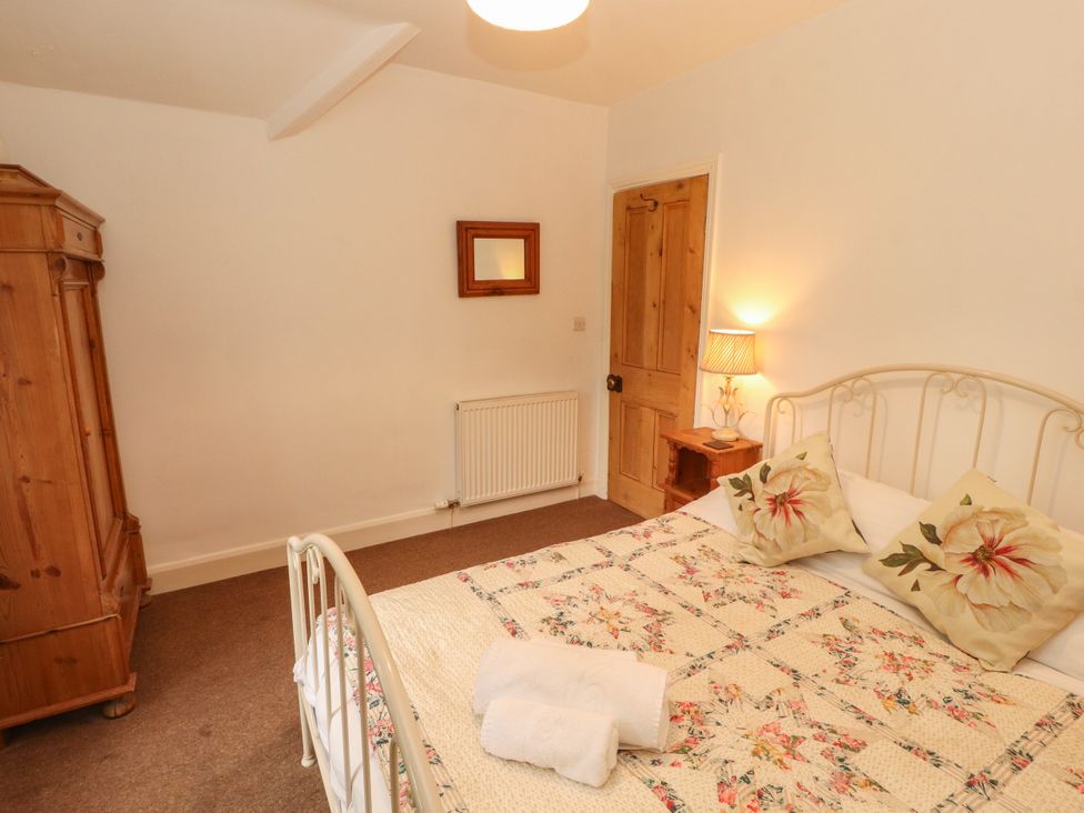 A bedroom with a bed and wardrobe at The Old Post House at Low Stott Park near Newby Bridge