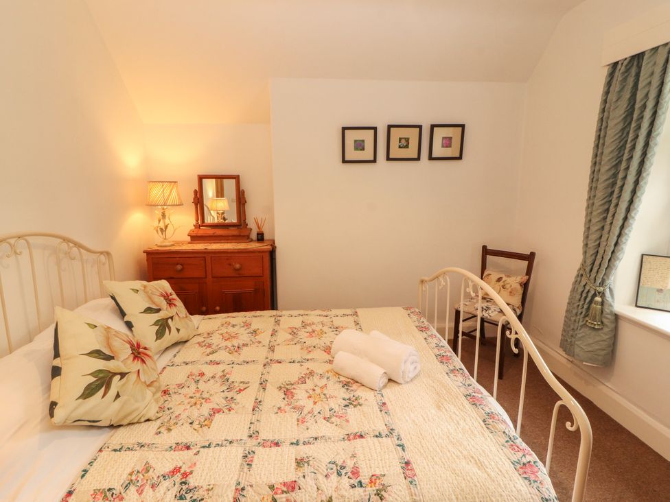 A bedroom with a bed and dresser at The Old Post House at Low Stott Park near Newby Bridge