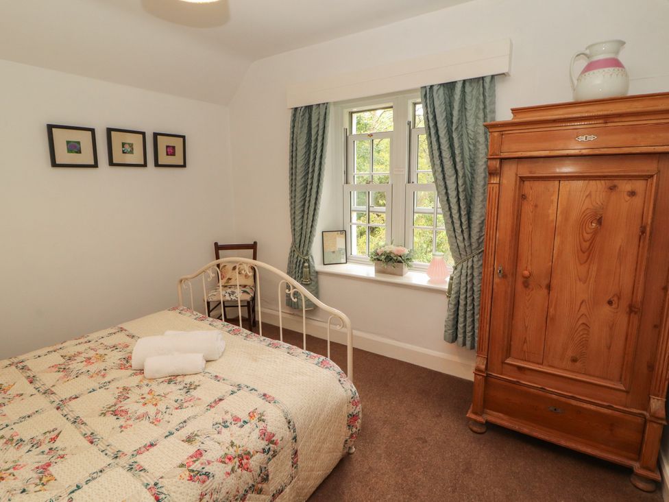 A bedroom with a bed and wardrobe at The Old Post House at Low Stott Park near Newby Bridge