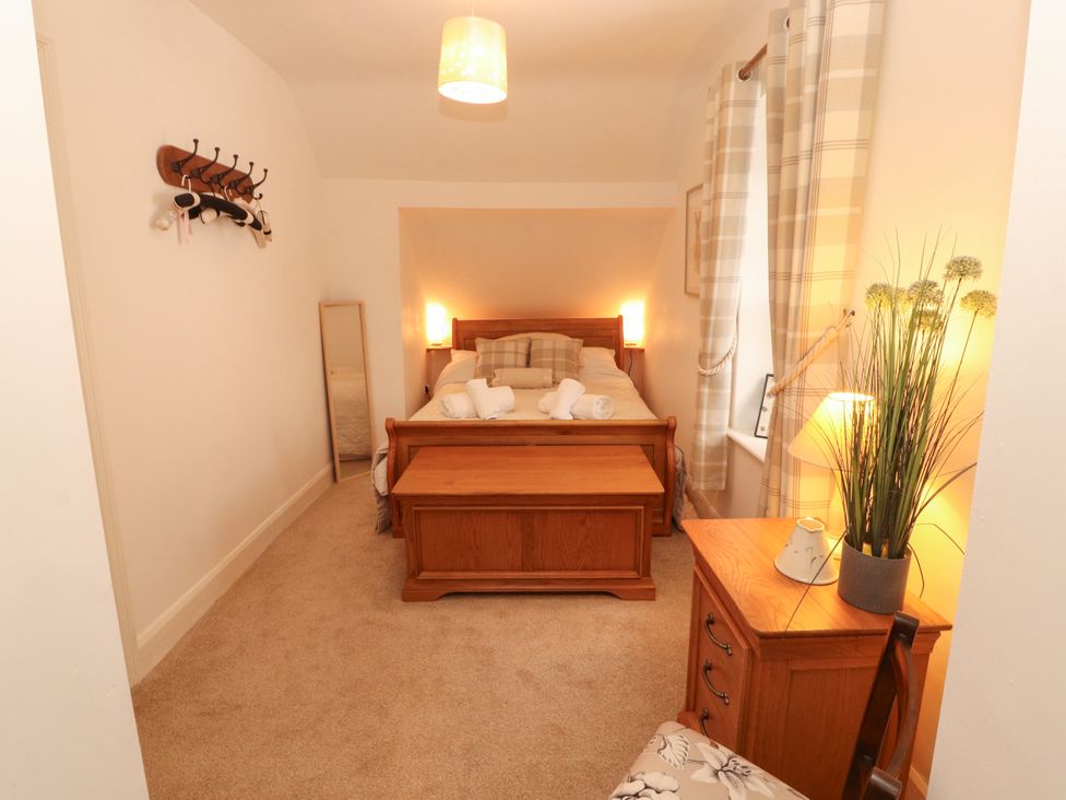 A bedroom with a bed and wooden furniture at The Old Post House at Low Stott Park