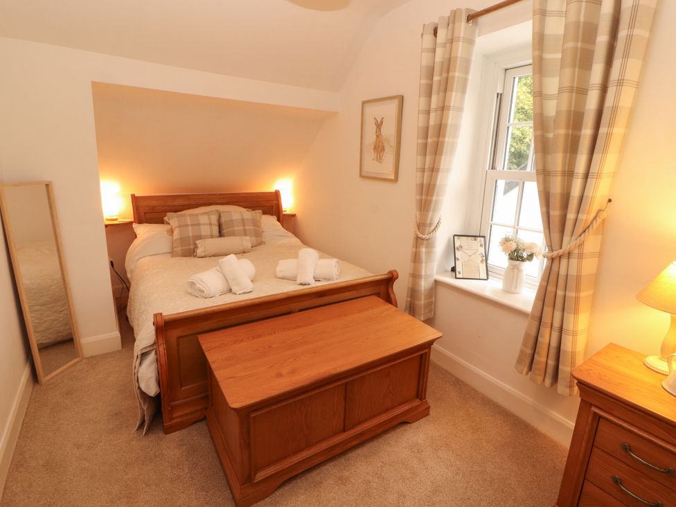 A bedroom with a bed and a mirror at The Old Post House at Low Stott Park near Newby Bridge