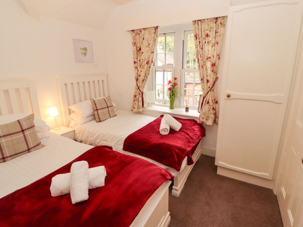 A bedroom with two beds and a window at The Old Post House at Low Stott Park near Newby Bridge