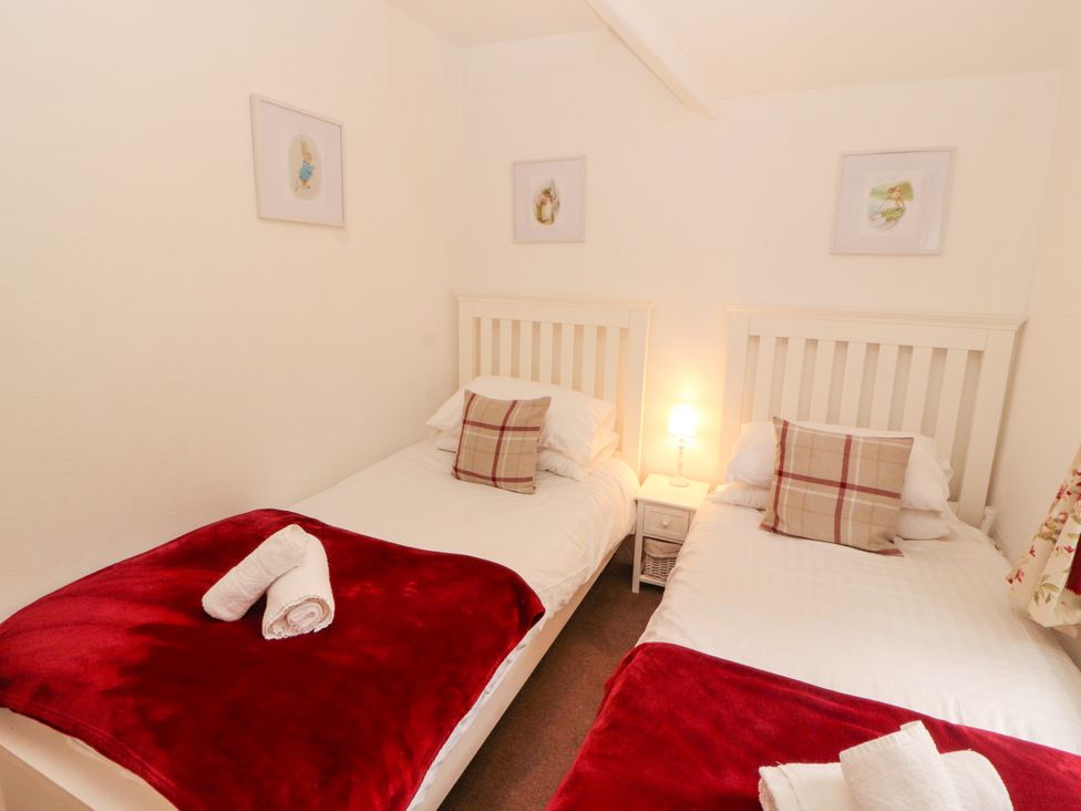 A bedroom with two beds and bedside table at The Old Post House at Low Stott Park near Newby Bridge