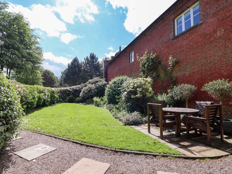 A garden with a table and chairs surrounded by plants at Carriage House Capesthorne near Chelford