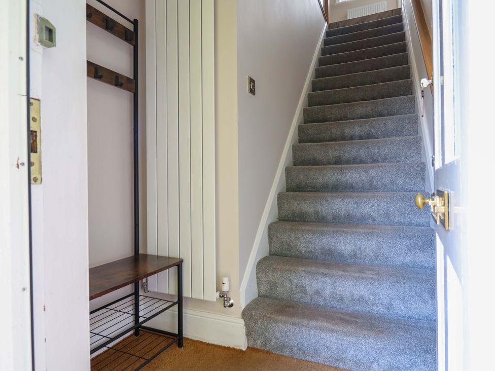 A hallway with a staircase and coat rack at Carriage House Capesthorne near Chelford