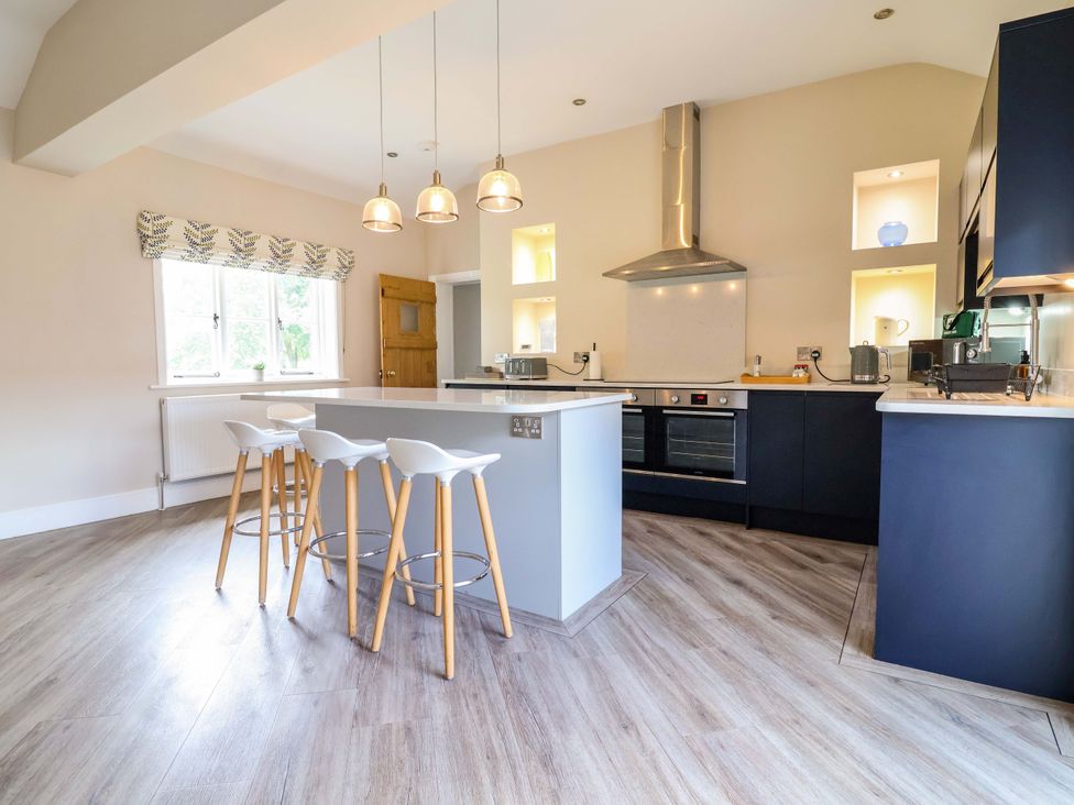 A kitchen with bar stools and a kitchen island at Carriage House near Chelford