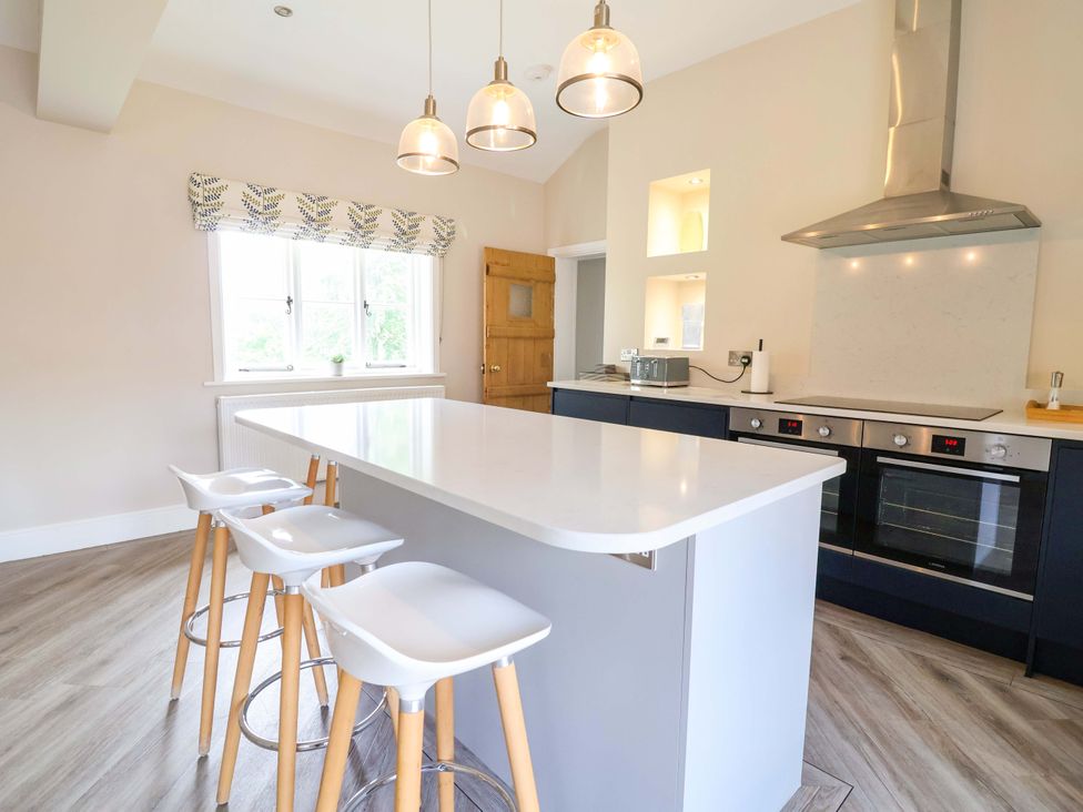 A kitchen with a large island and bar stools at Carriage House in Capesthorne near Chelford