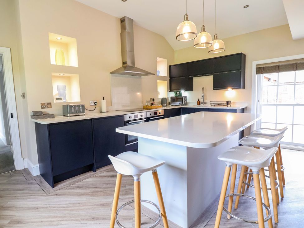A kitchen with a large island and bar stools at Carriage House Capesthorne near Chelford