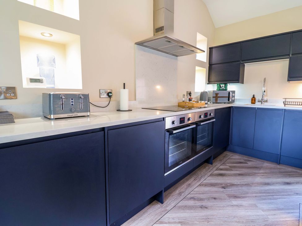A kitchen with dark cabinets and modern appliances at Carriage House in Capesthorne near Chelford