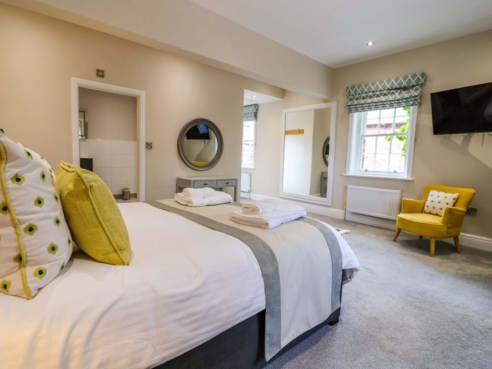 A bedroom with a bed and armchair at Carriage House Capesthorne near Chelford