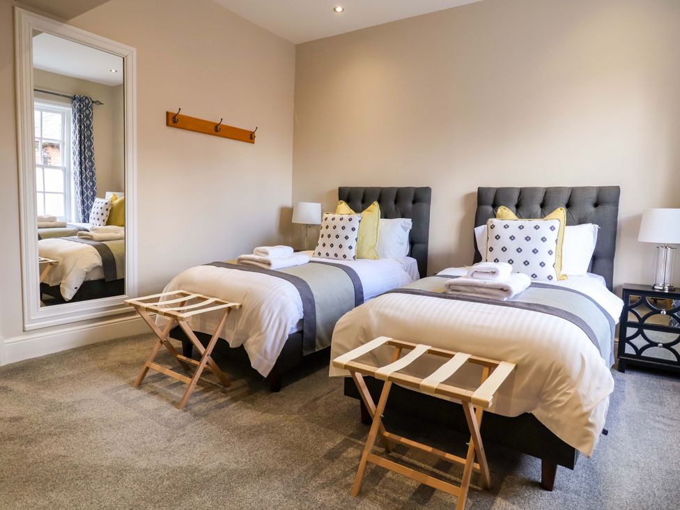 A bedroom with twin beds, a mirror, and a side table at Carriage House in Capesthorne near Chelford
