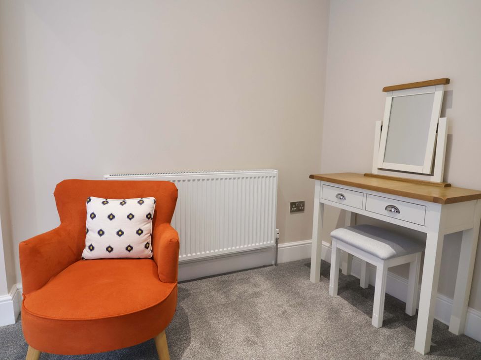 A bedroom featuring an armchair, vanity table, and radiator at Carriage House in Capesthorne near Chelford