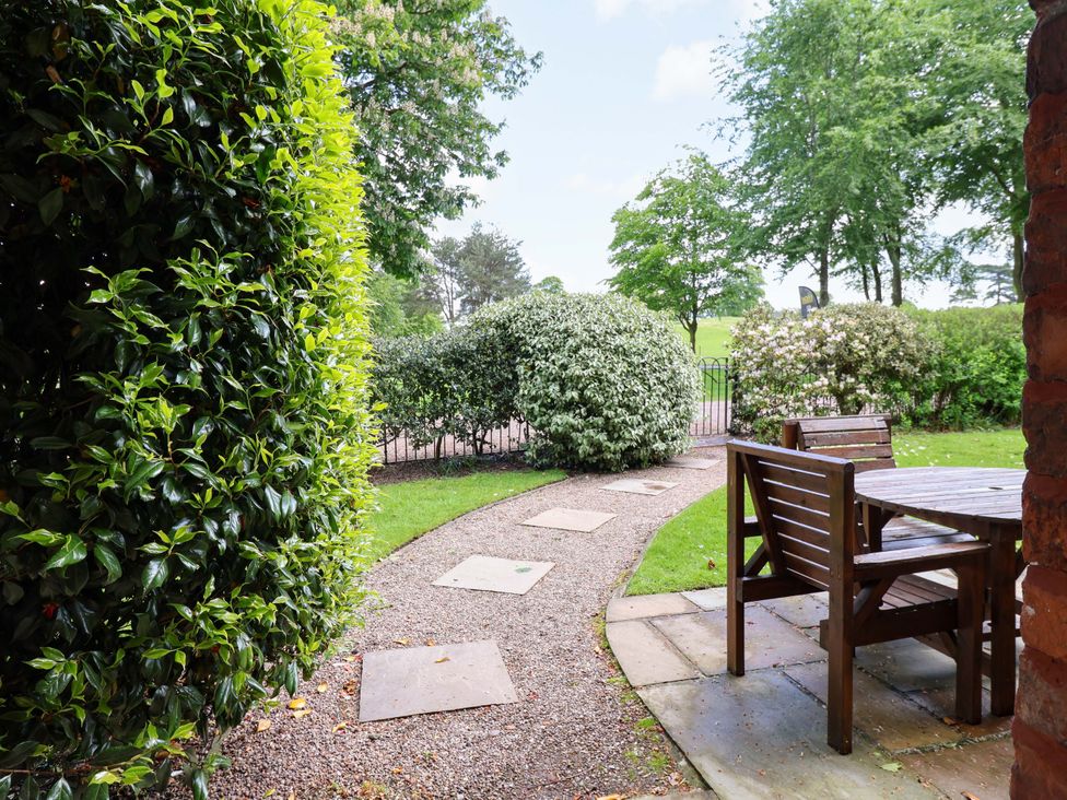 A garden with a pathway leading to furniture at Carriage House in Capesthorne near Chelford