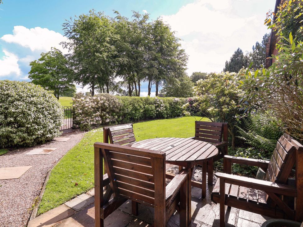 A garden with a table and chairs at Carriage House Capesthorne near Chelford