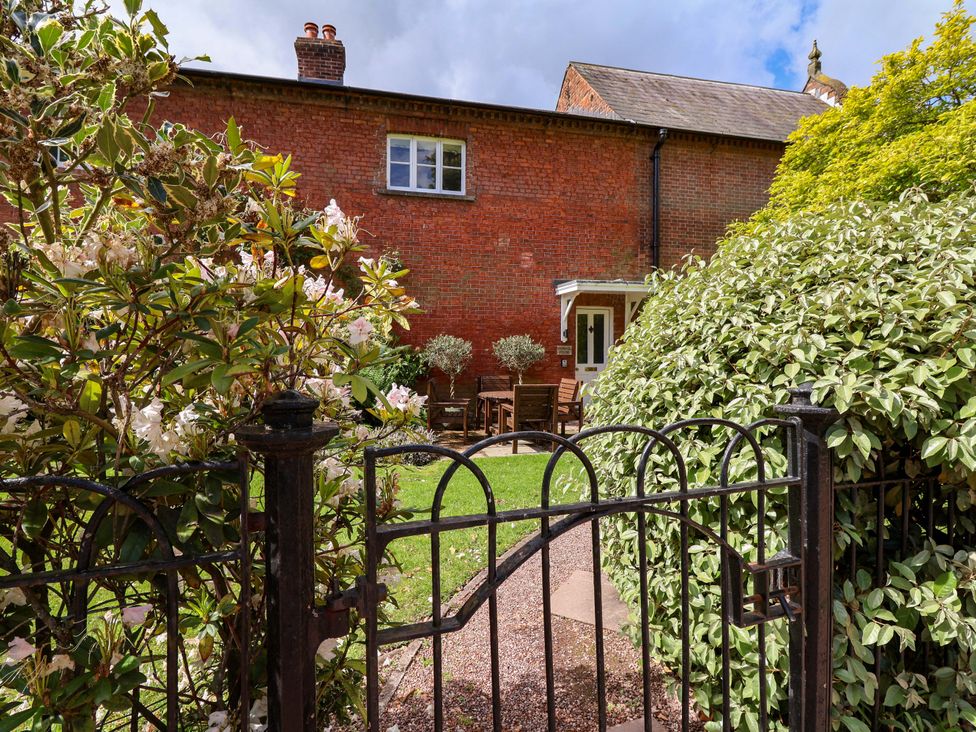 A garden with a wooden table and chairs at Carriage House near Chelford