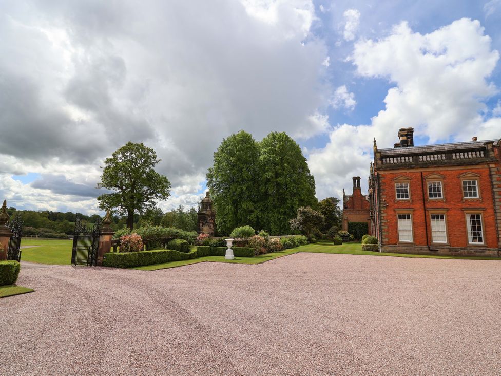 An outdoor area with a gravel parking area and trees at Carriage House Capesthorne near Chelford