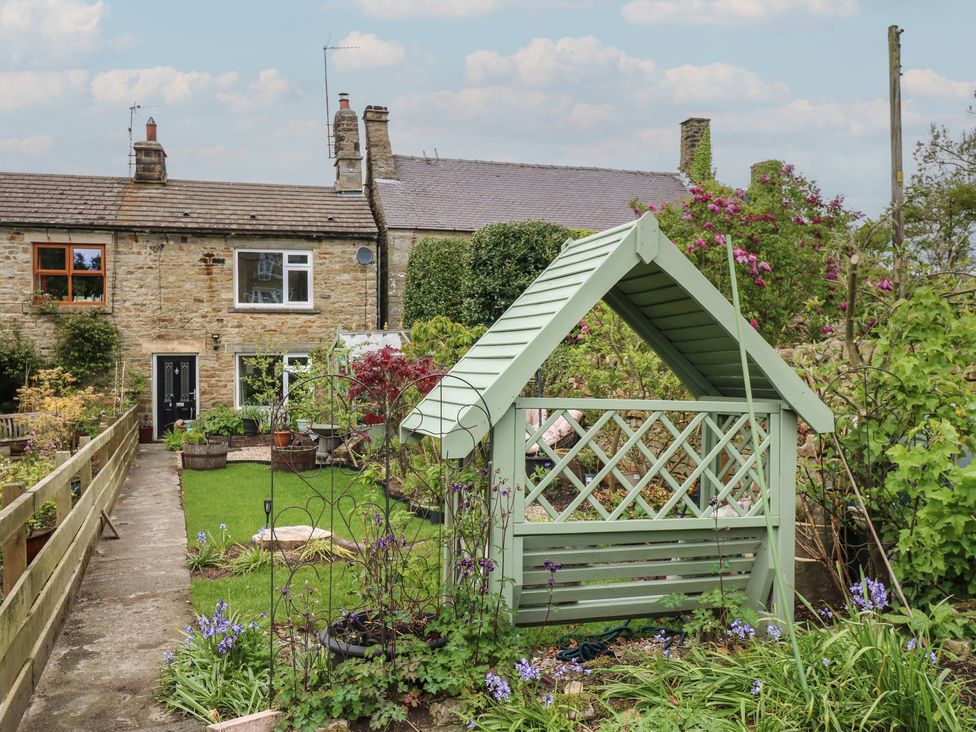 A garden with a greenhouse and flowers at Banklands in Barnard Castle