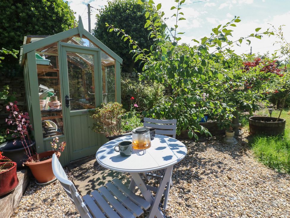 A garden with a greenhouse and a table set for tea at Banklands Mickleton, Teesdale