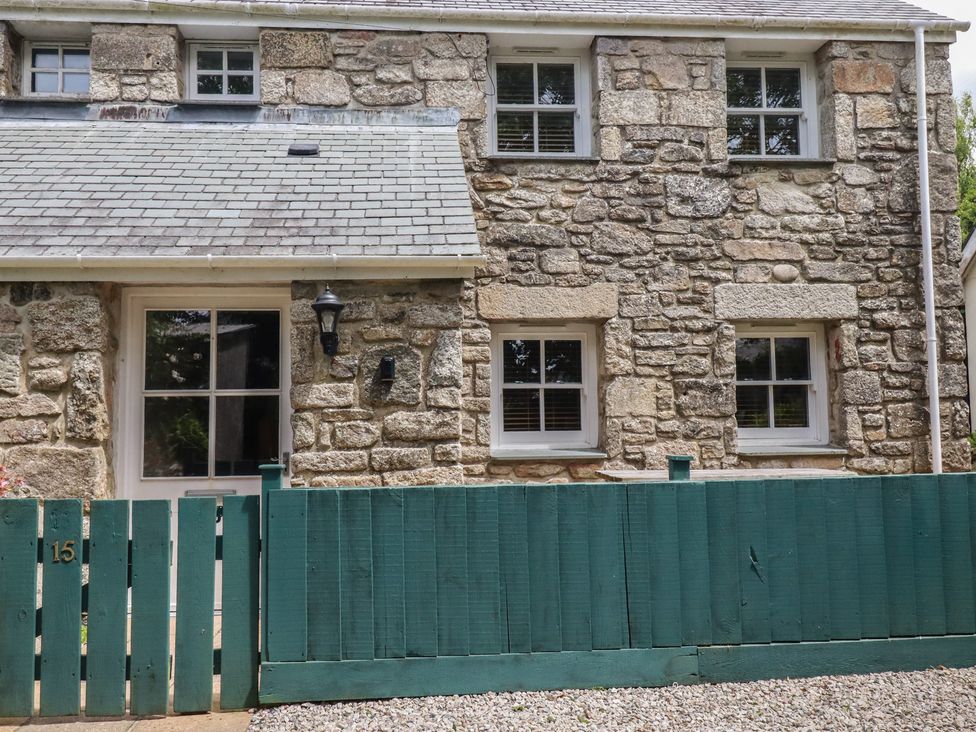 An exterior view of a stone cottage with a green fence at 15 Boscaswell Downs Pendeen