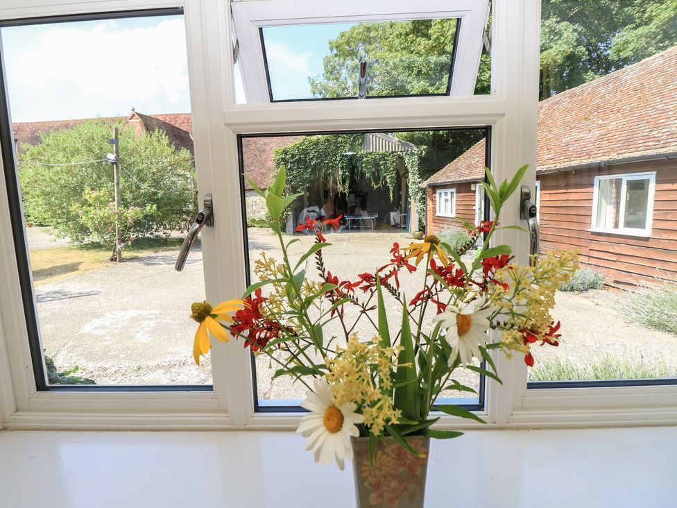 A view through a window with flowers in a vase at Byre Cottage 3 Sullington near Storrington
