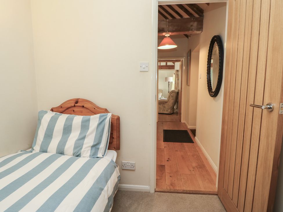 A bedroom with a single bed and a door leading to a hallway at Byre Cottage 3 Sullington near Storrington