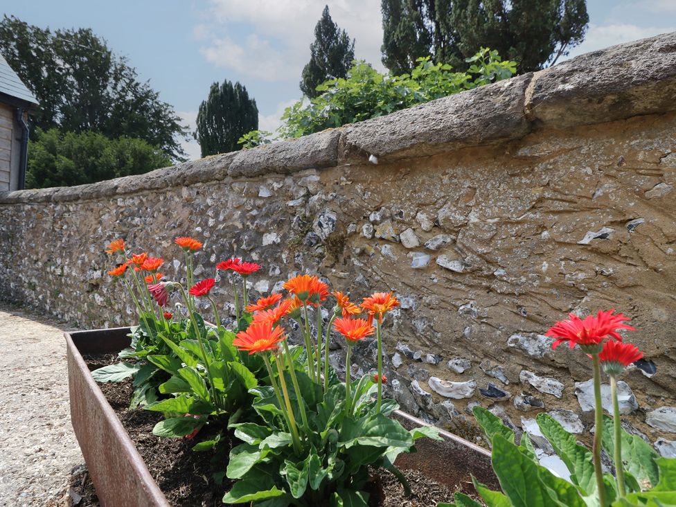 A garden with flowers in a bed beside a stone wall at Byre Cottage 3 Sullington near Storrington