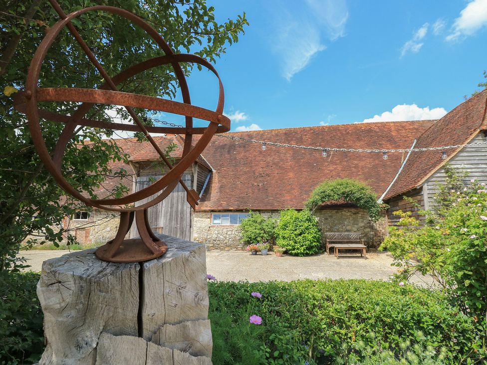 An armillary sphere and wooden bench in a garden at Byre Cottage 3 Sullington near Storrington