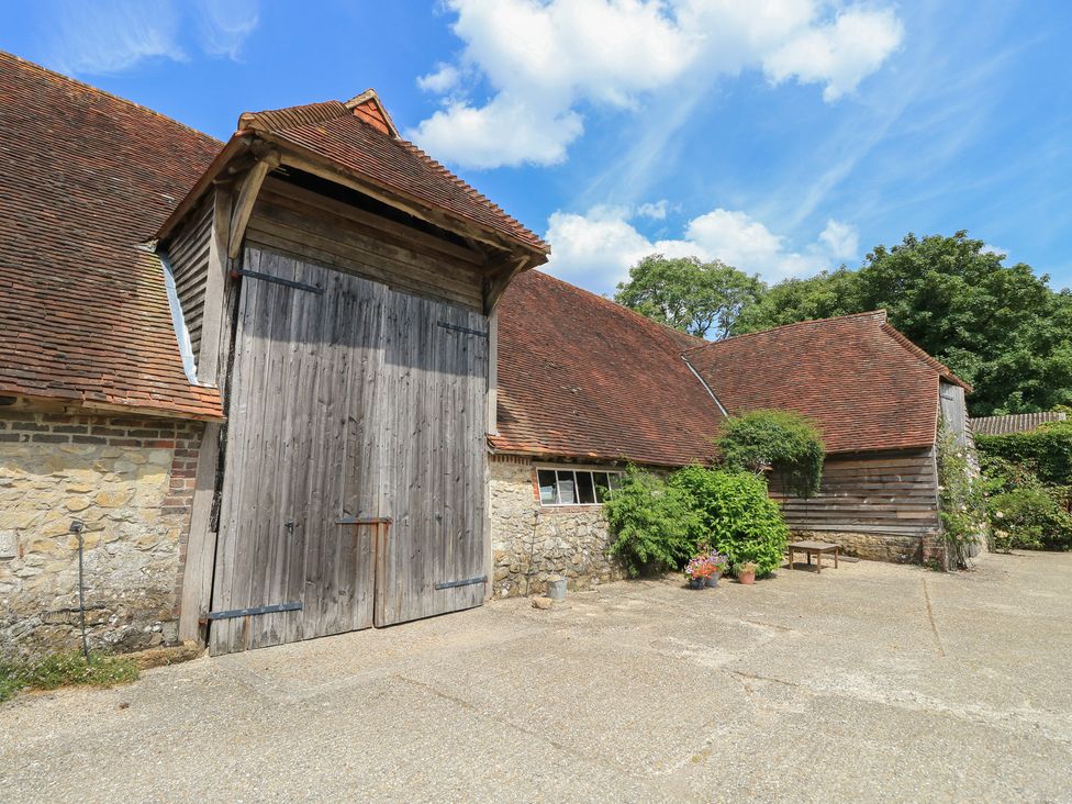A barn with wooden doors and stone wall at Byre Cottage 3 Sullington near Storrington