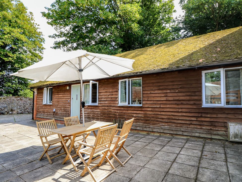 An outdoor dining area with a table and chairs at Byre Cottage 2 Sullington near Storrington