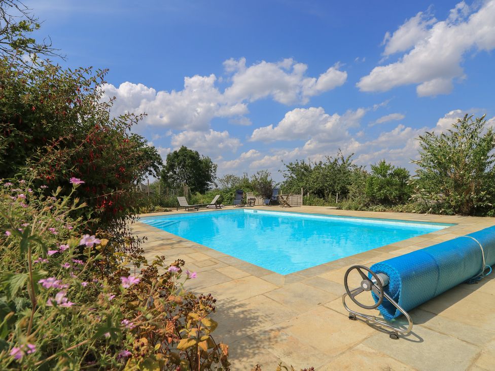 An outdoor area with a swimming pool and deck chairs at Byre Cottage 2 Sullington near Storrington