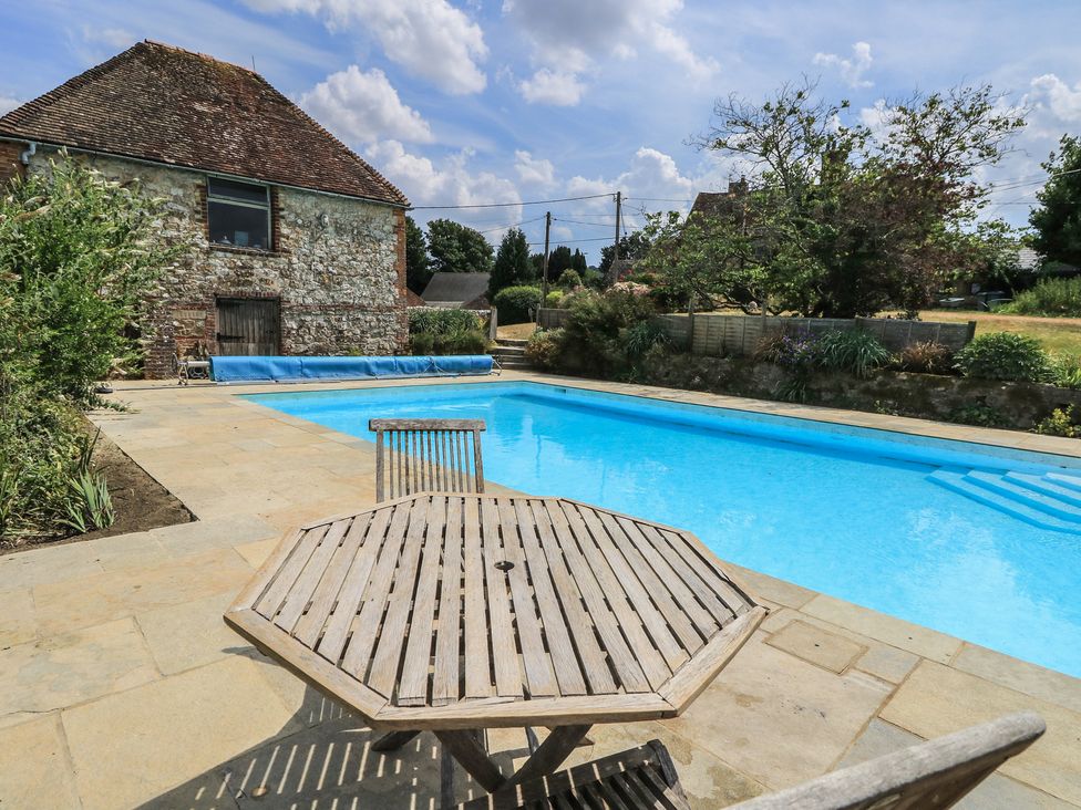 An outdoor area with a swimming pool and a table at Byre Cottage 2 Sullington near Storrington