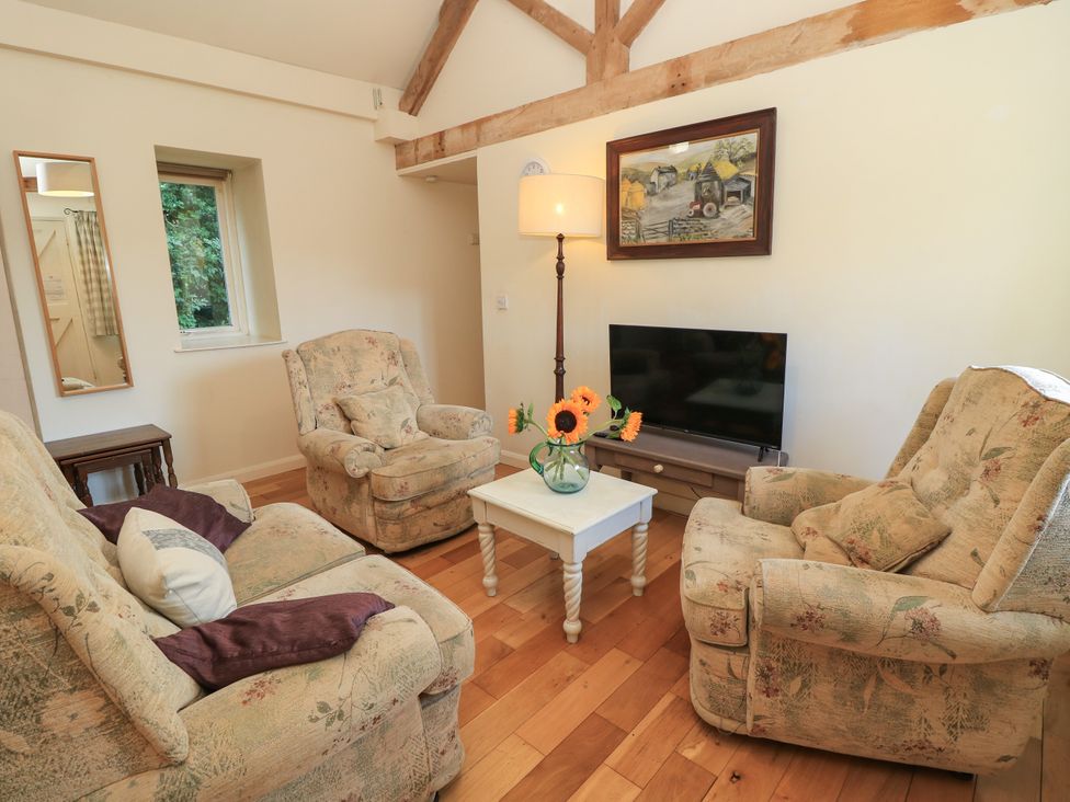 A living room with a television and coffee table at Byre Cottage 2, Sullington near Storrington
