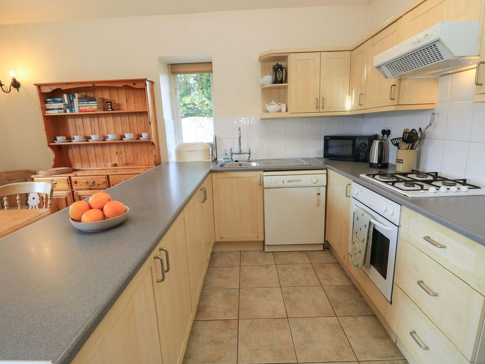 A kitchen with wooden cabinets and modern appliances at Byre Cottage 2 in Sullington near Storrington
