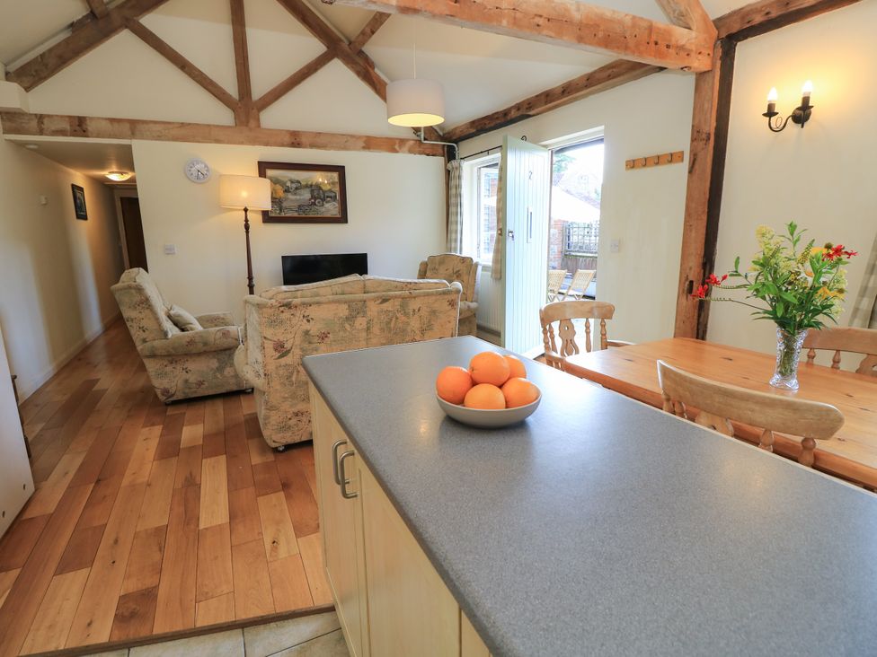 A living room with a sofa, table, and television at Byre Cottage 2 Sullington near Storrington