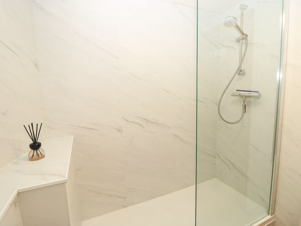 A shower with glass door and tiled wall at Byre Cottage 2 Sullington near Storrington