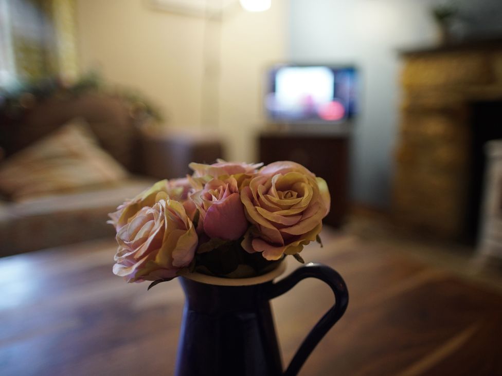 A vase with roses on a coffee table in a living room at The Old Dairy in Bridport