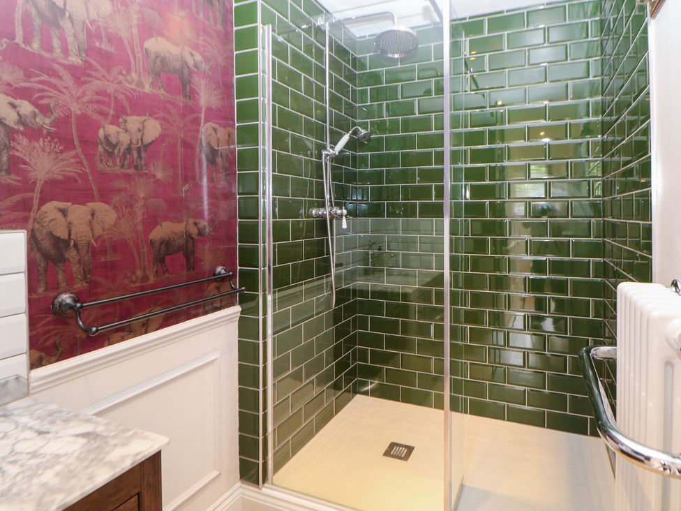 A shower with green tiles and a towel rail at Church View in Buxton