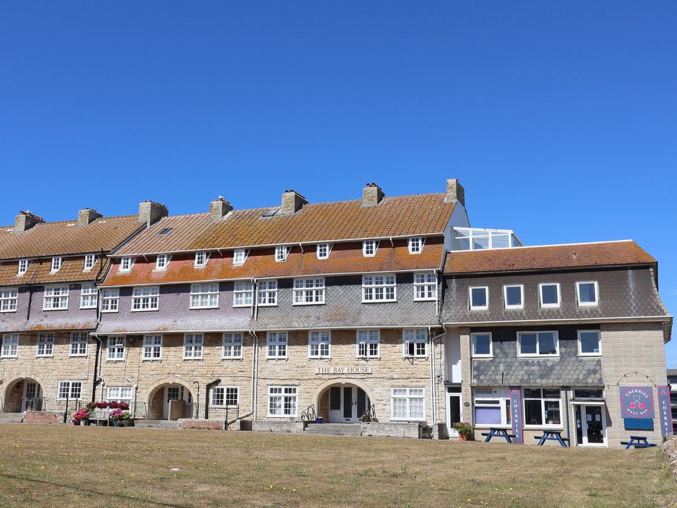 A building exterior with various windows and a sign at Flat F