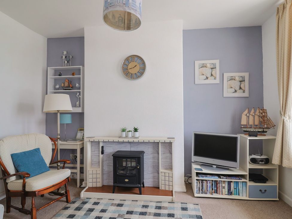 A living room with a fireplace and bookshelf at Flat F